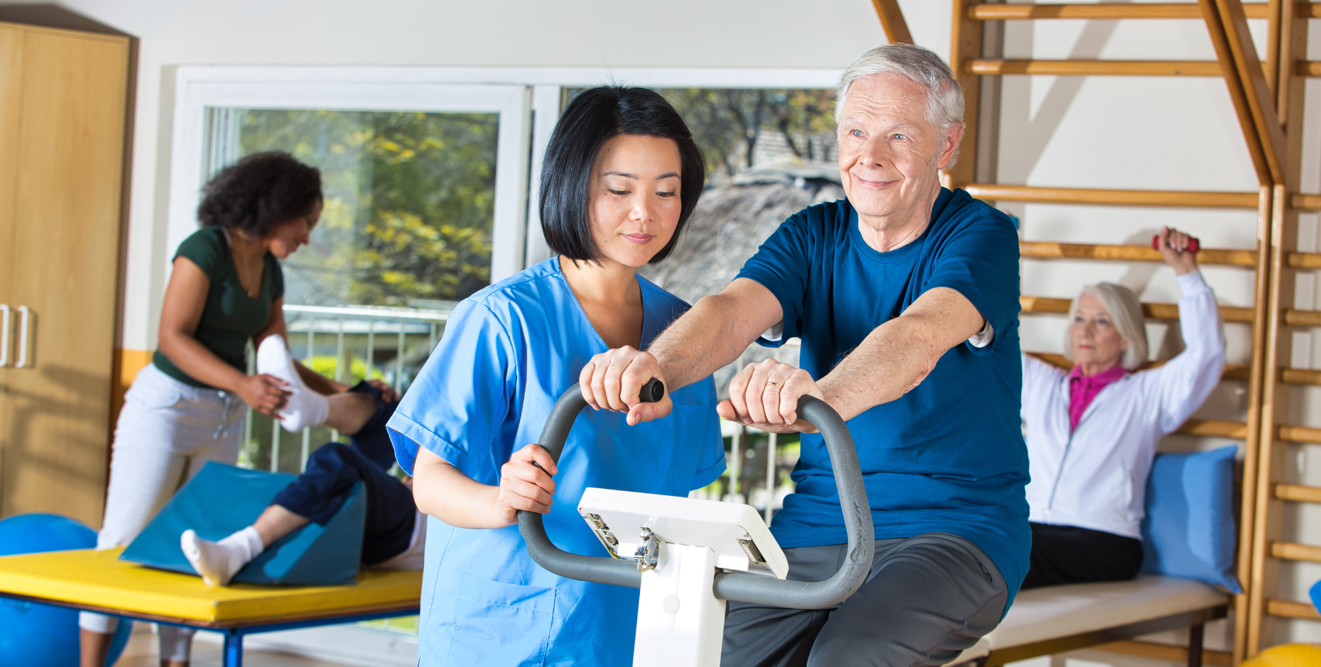 Older person being taken through their rehabilitation exercises on a bike by their physiotherapist