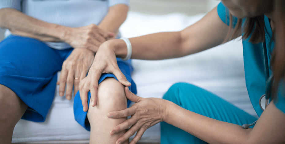 A clinician examines a patient's knee. 