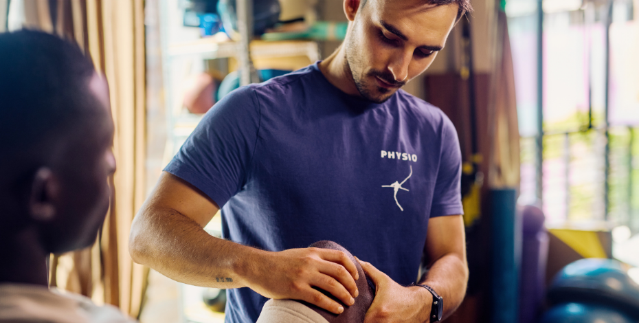 a physiotherapist examines the knee of his patient.