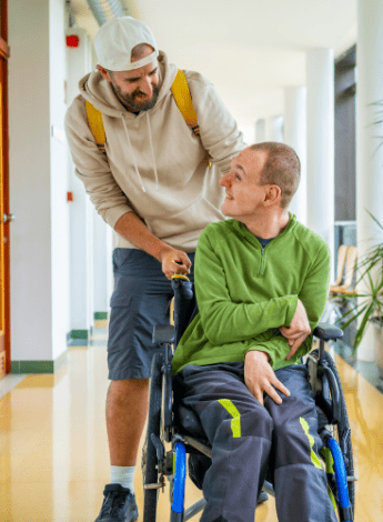 A man with cerebral palsy having his wheelchair pushed by a friend 