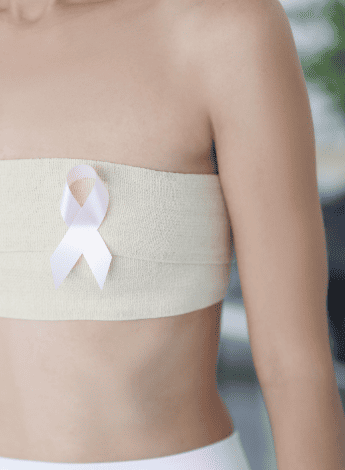 The image shows the torso of a woman with a bandage wrapped around her breasts