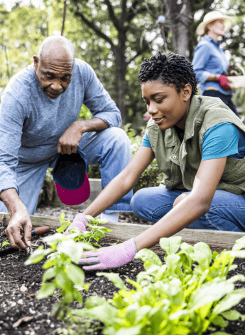 Two people of colour are outside doing some gardening. 