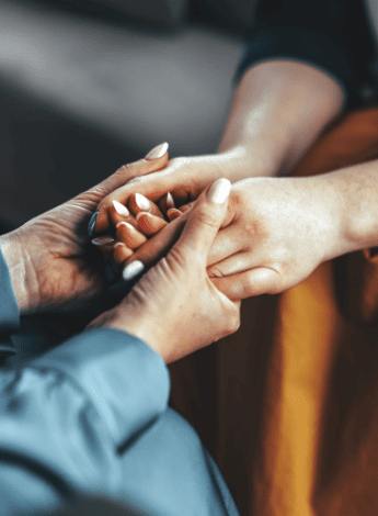 The image is of a person is holding another's hands in theirs. Only the hands can be seen, not the people. 