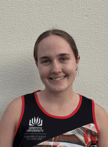 the image is of a smiling woman with her hair pulled back. She is wearing a basketball singlet. 
