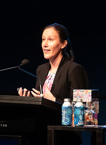 A woman with a ponytail is standing behind a podium talking. 