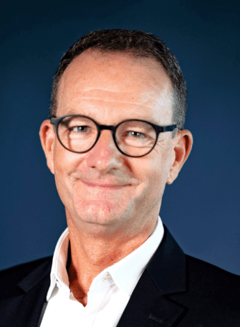 A man with dark hair and glasses in a suit
