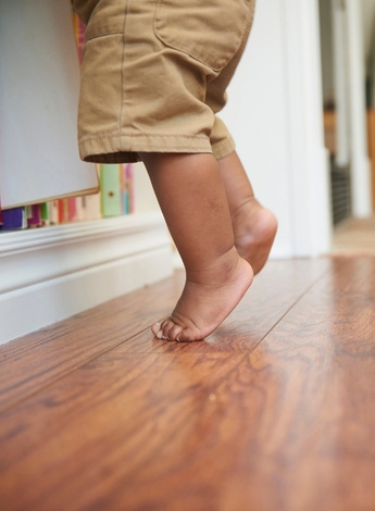 The image is of a toddler on tiptoes, seen from the top of the legs down. 