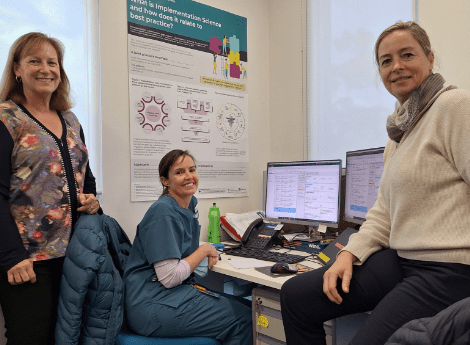 Three researchers sitting and standing around a desk