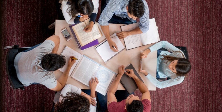 Arial view of students sitting around a table with books and other study devices