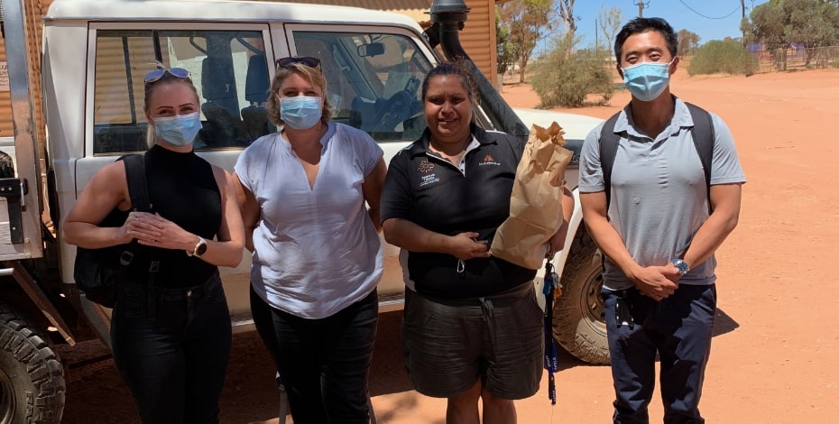 The Fly2 Health Group team standing in front of a car in the outback. 
