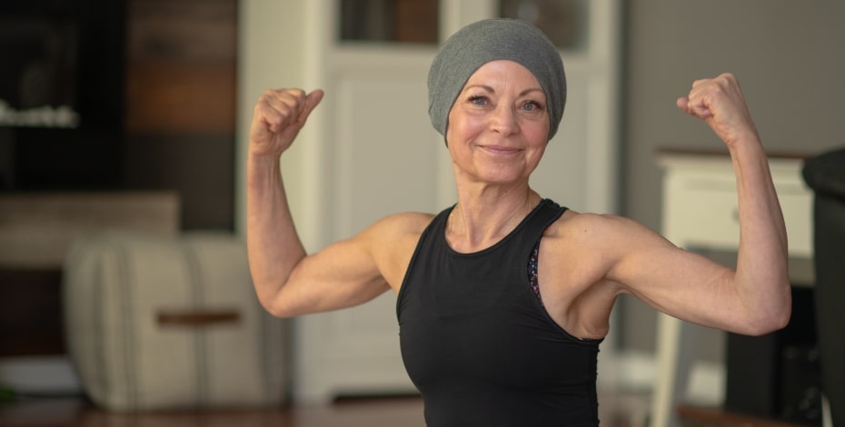 Woman with scarf around her head flexes biceps.