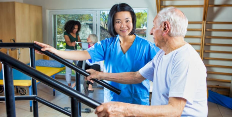 A physio helps a patient practise walking. 