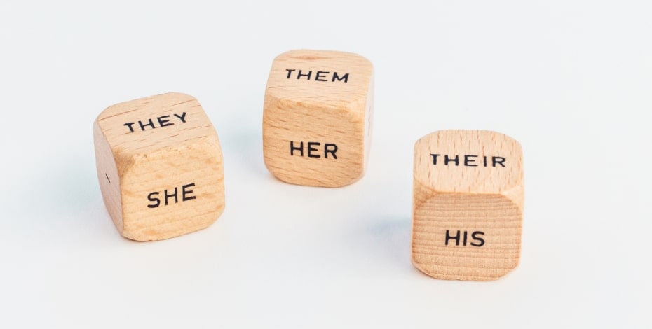 Three wooden dice with a range of pronouns on them. 