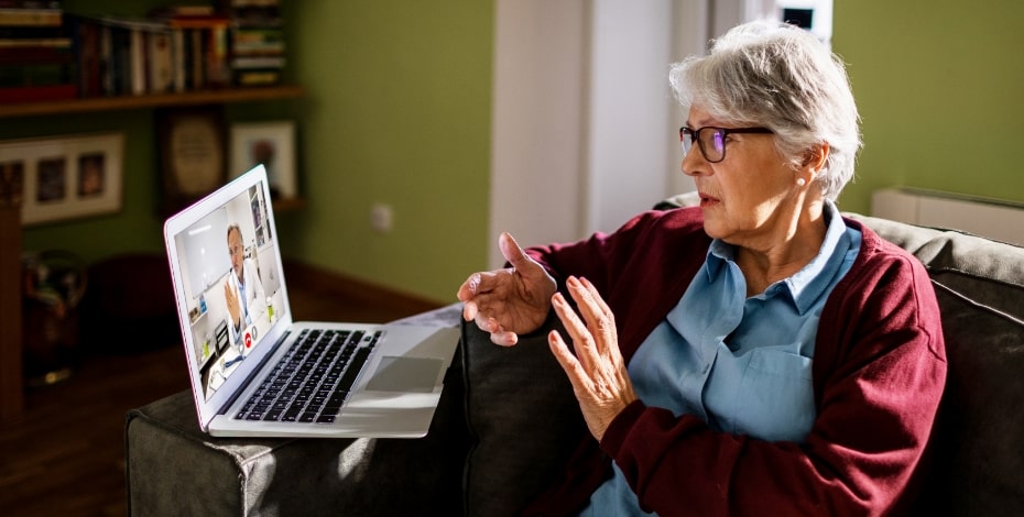 A woman consults a physiotherapist via telehealth on a computer screen.