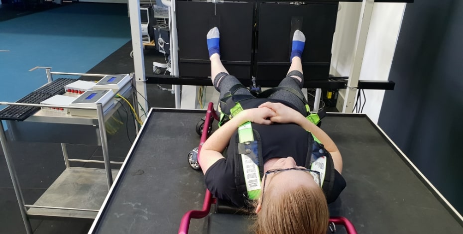 A person is lying on a platform with their feet against a board