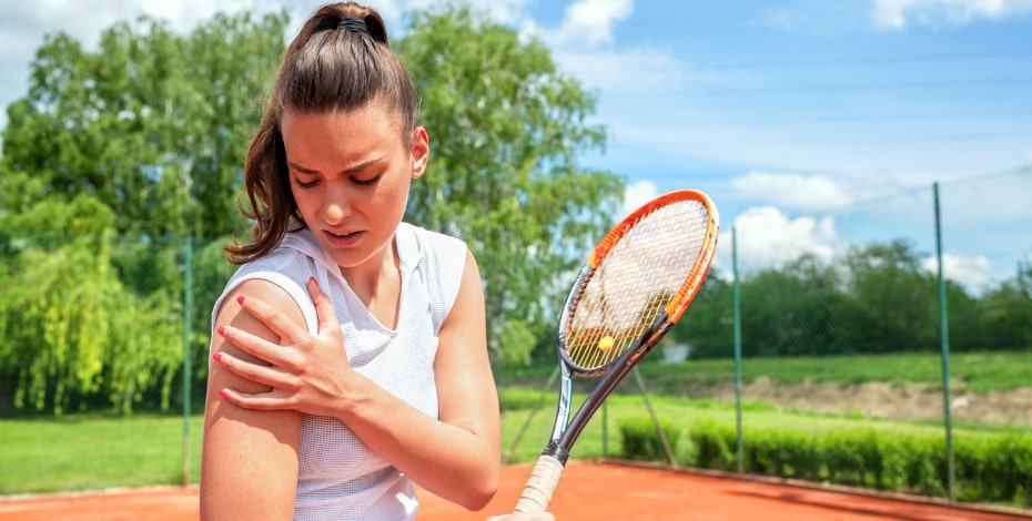 A tennis player holds her shoulder as if it hurts.