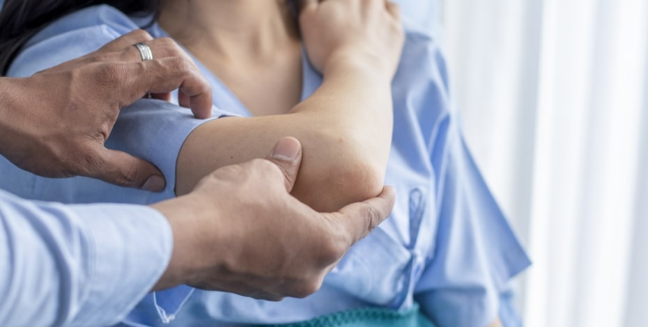 A physiotherapists manipulates a person's elbow joint