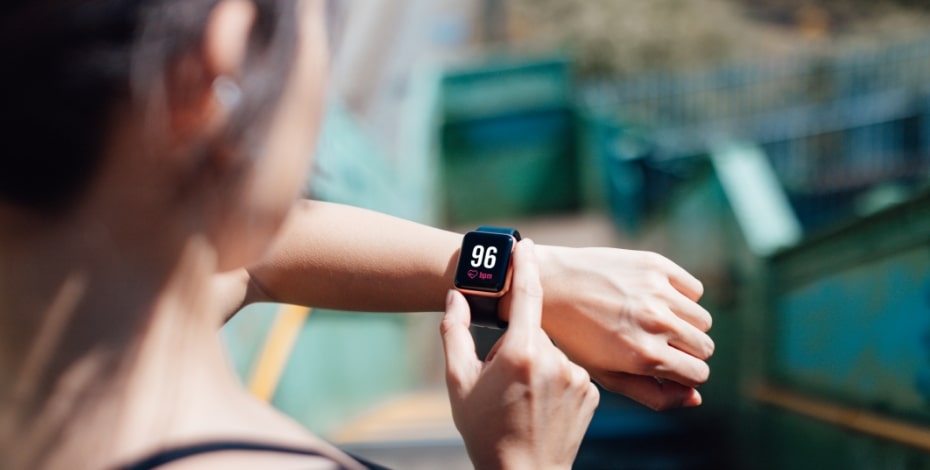 A woman facing away from the camera checks her smart watch