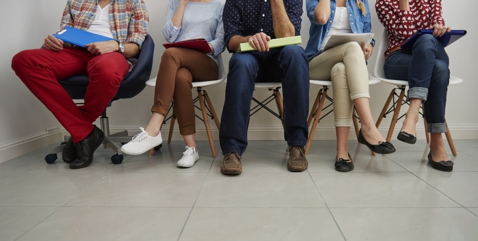 Legs of people sitting in chairs waiting.