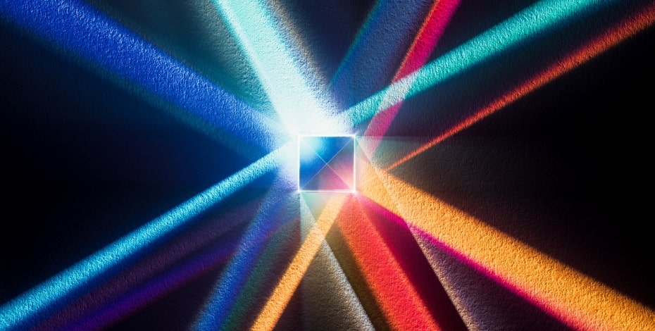 Abstract image of coloured bands of light intersecting in a black void with a glowing centre ball.