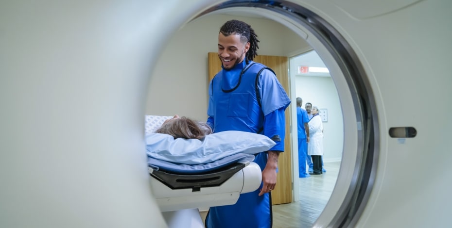 A medical technician smiles at a patient about to go into an MRI.