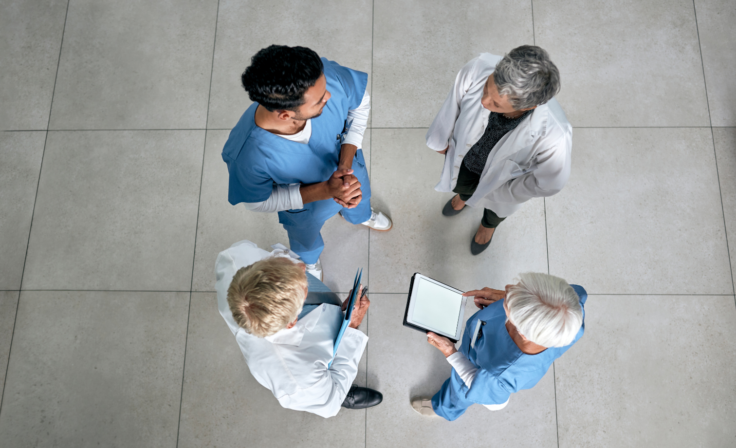 Four health care professionals standing facing each other engaged in a group discussing 