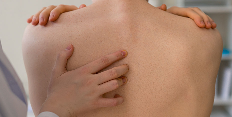 A hand touching a naked human upper back.