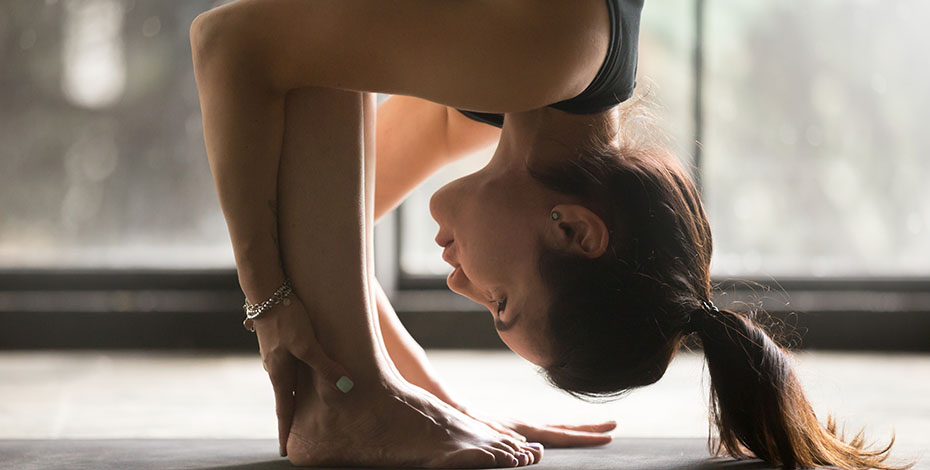 A woman in a yoga position where her head is touching her knees. She is showing off big time.