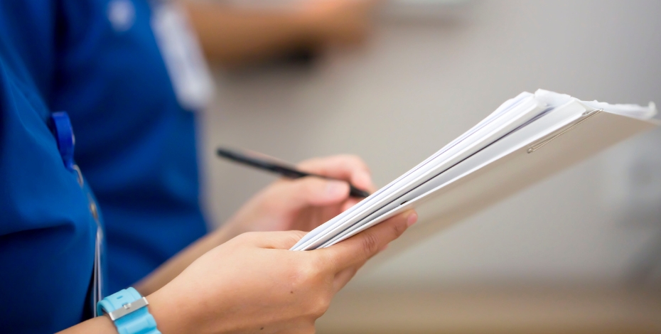 close up mid shot of people in blue scrubs holding pieces of paper and a pen