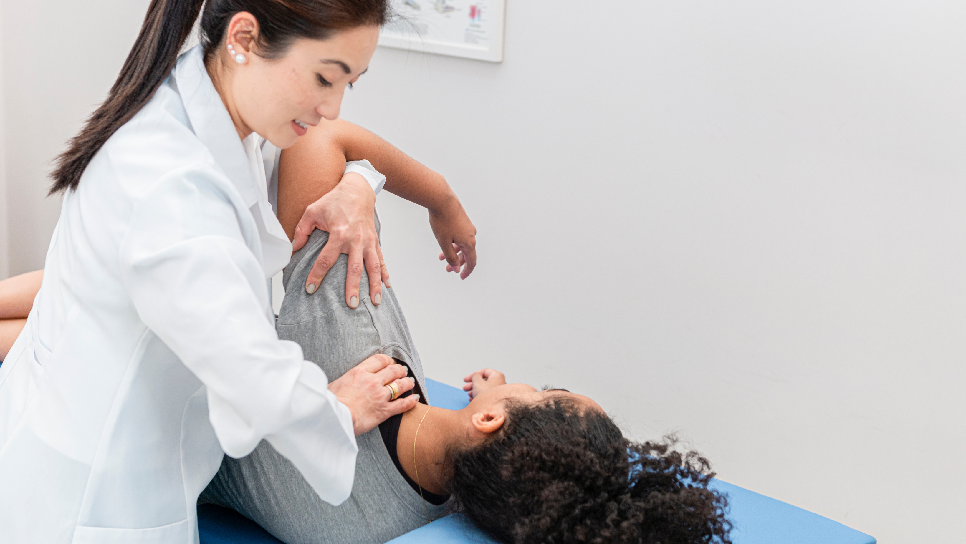 A practitioner is treating a patient's shoulder who is lying down on their side.