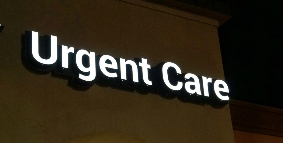 The outside of a building with a sign saying 'Urgent Care' lit up on it.