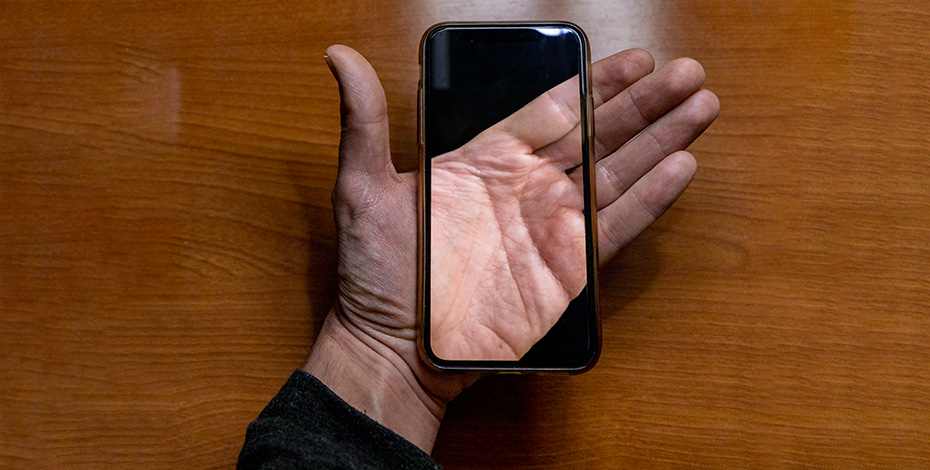 A hand highlighted by a mobile phone.