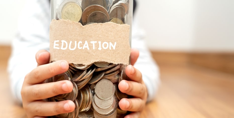 The image shows a jar of coins with the label Education on it. Someone is holding the jar. 