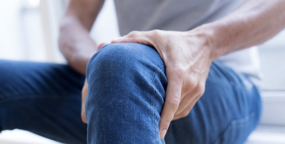 A man clutching his knee as if in a lot of pain.