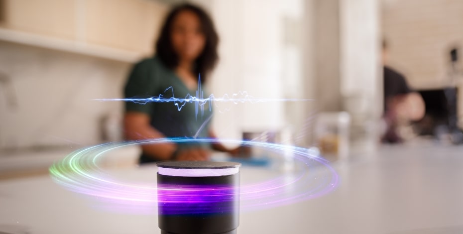 The image shows an Alexa device on a benchtop, with some swirling lines around it to indicate that its active. In the background a woman is looking at the device. 