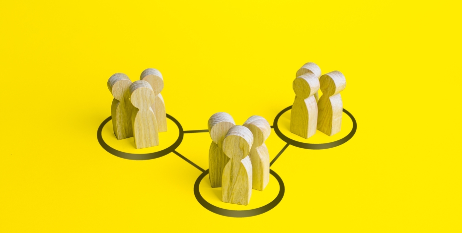 yellow background of wooden people in different groups forming a triangular shape