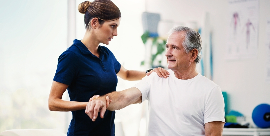 A physio holding the arm of an older patient in a clinical setting
