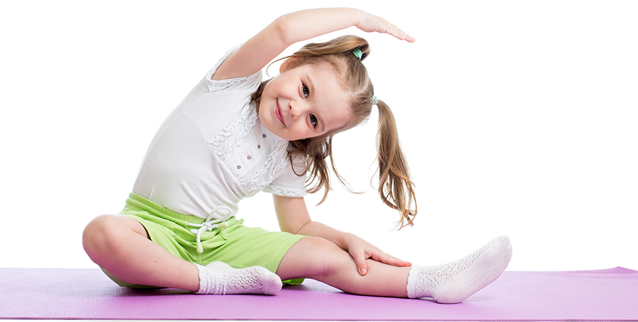 Image of a young girl seated on the floor doing a stretching exercise. She is happy.