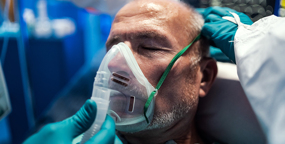 Man in intensive care with oxygen mask on his face.