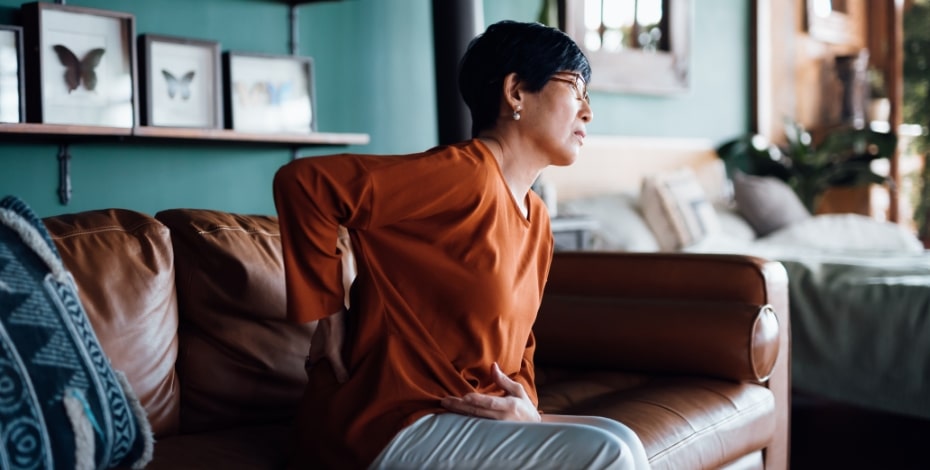 person sitting on the couch with pain in their lower back