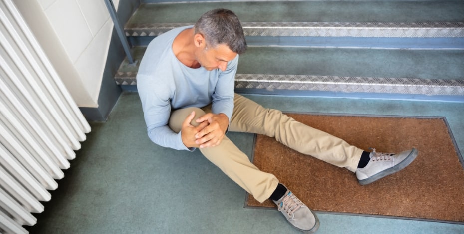 person with injured leg sitting at the bottom of a staircase