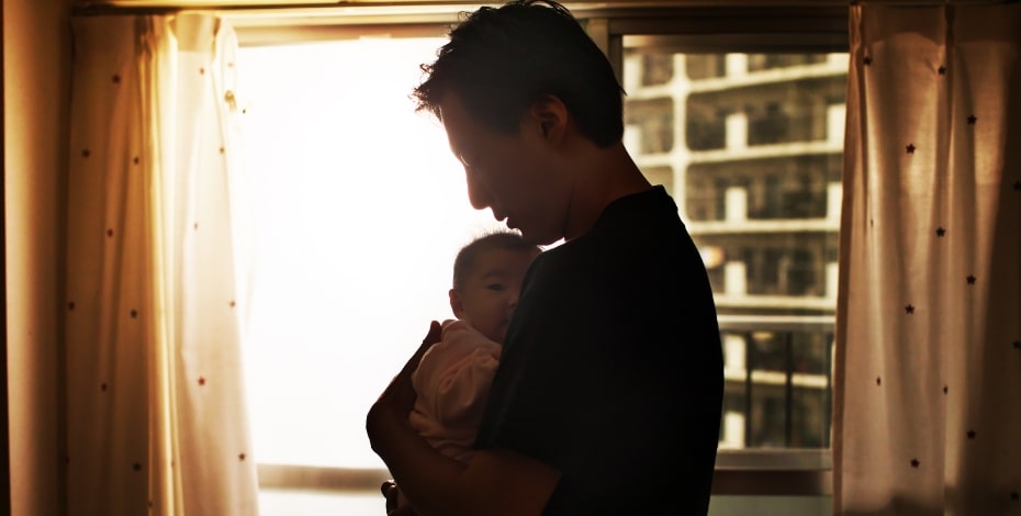 A silhouetted father cradles a newborn baby.