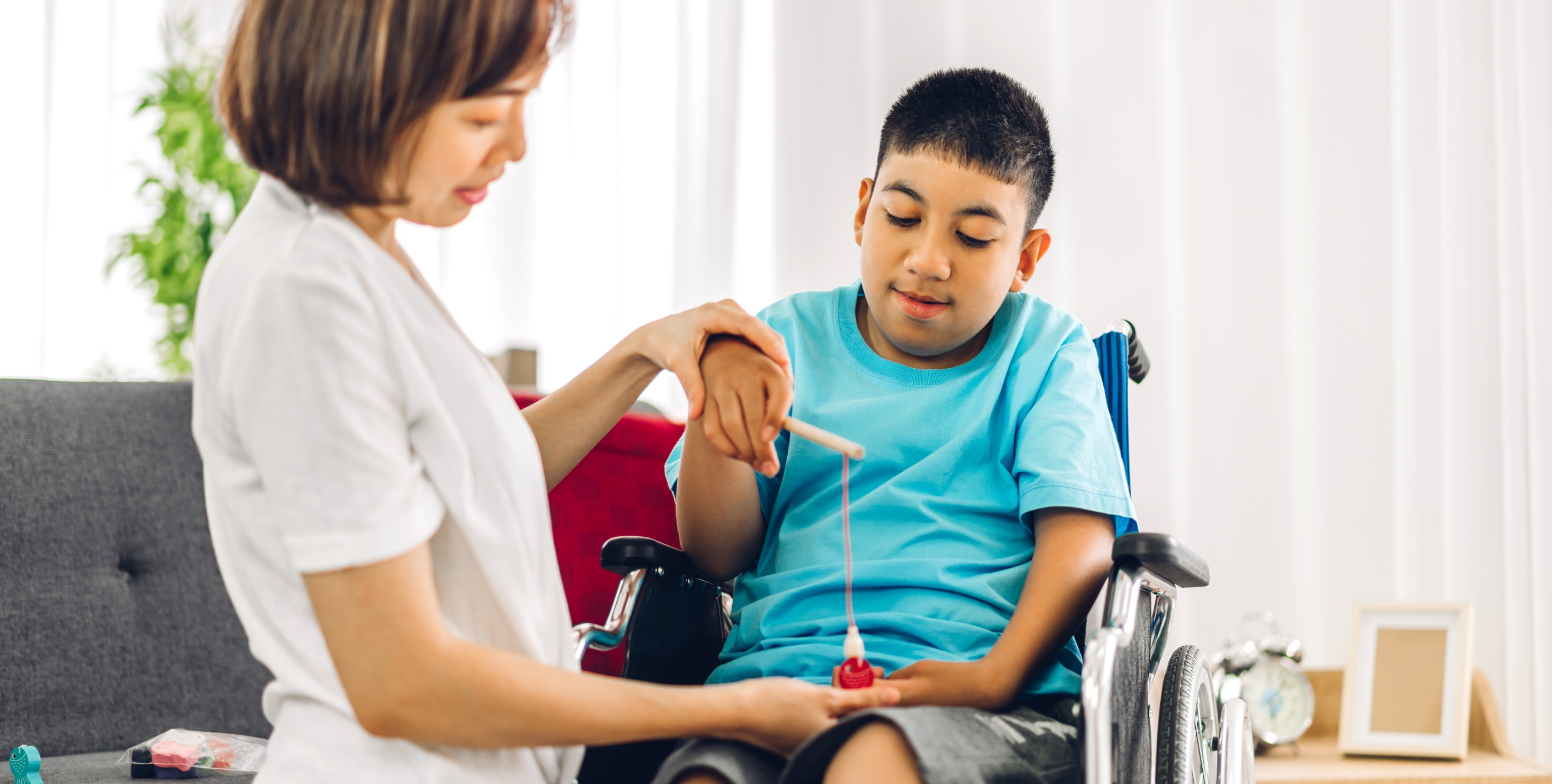 young boy in wheelchair doing a hand exercise with a physiotherapist