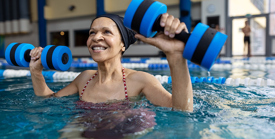 A woman is using hand weights in a pool. 