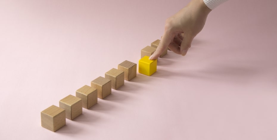 Building blocks, one highlighted in yellow with a hand pointing at the yellow block