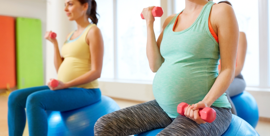 Pregnant women sitting on exercise balls holding weights