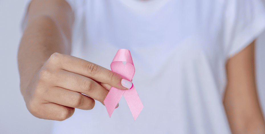 Woman in a white t-shirt holds up a pink ribbon, to represent breast cancer awareness