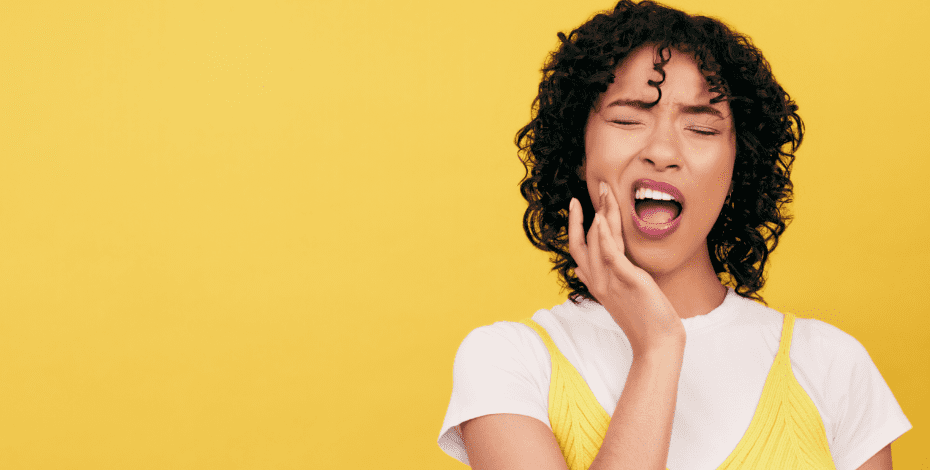 A woman touches her jaw in pain