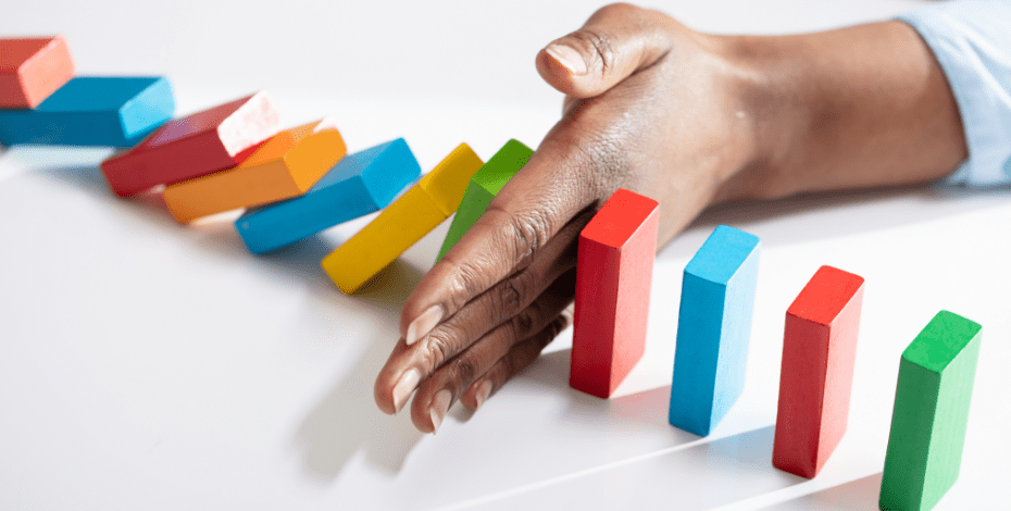 Image of a hand stopping dominoes from falling