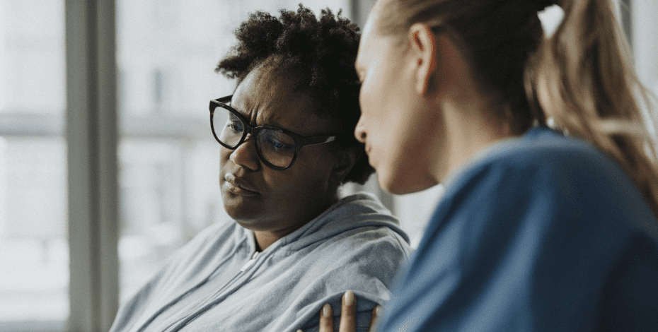 A women with a blonde ponytail is comforting another woman. 